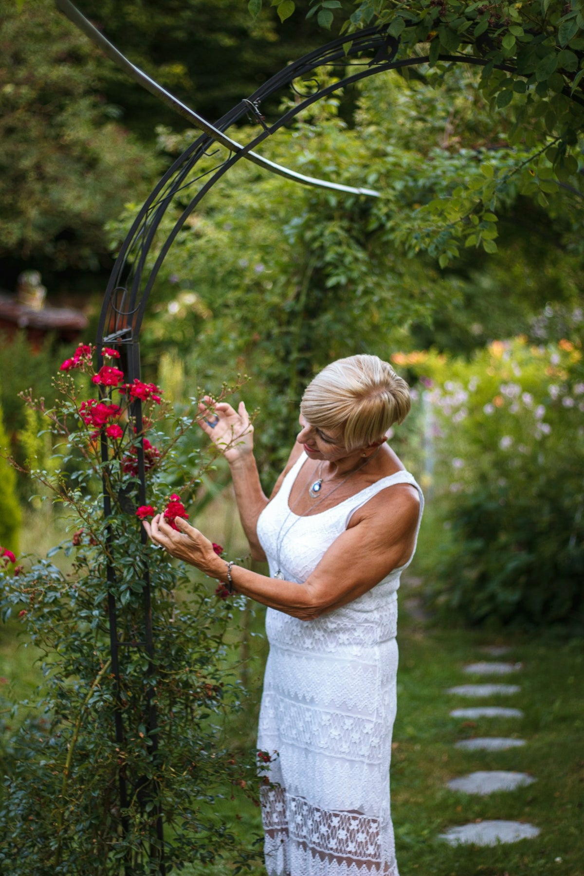 Woman in a light white summer dress in a rose garden