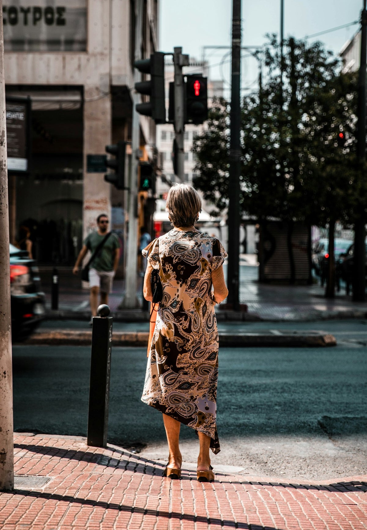 Woman in a long printed dress crossing a city street